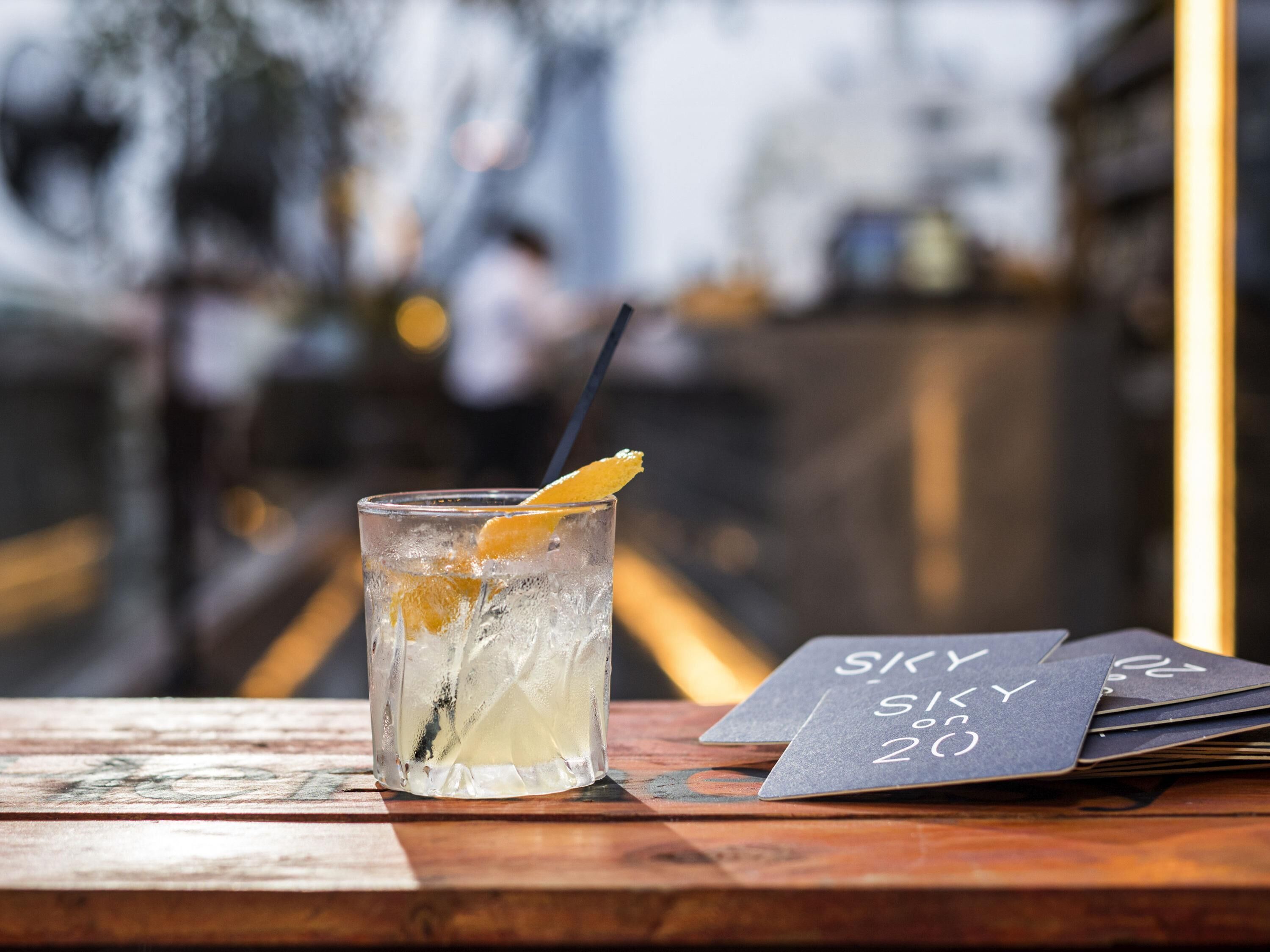 A glass of iced drink with a lemon slice on a wooden table with menus.
