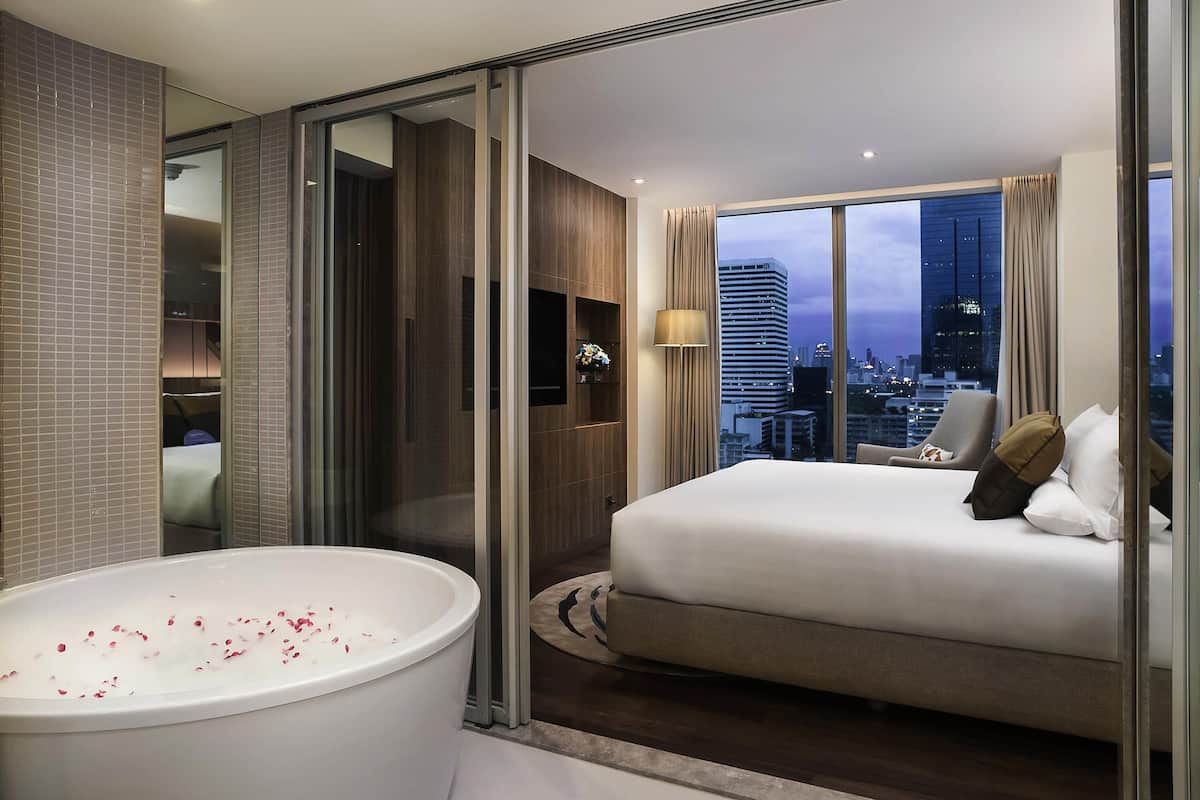Habitació d'hotel moderna amb un llit gran, una banyera i vista a la ciutat.