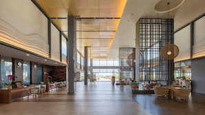 A spacious lobby with a reception desk, seating areas, and a large window offering a view of the outdoors.