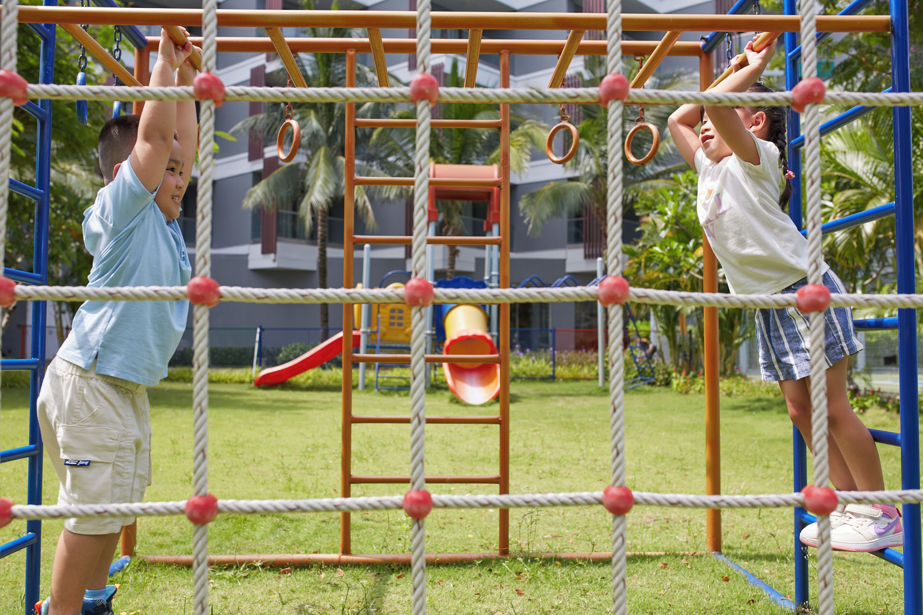 Un parque infantil con una estructura de cuerdas, un tobogán y una pared de escalada.