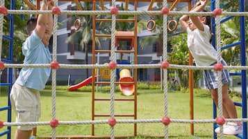 Un parque infantil con una estructura de cuerdas, un tobogán y una pared de escalada.