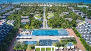 A resort with multiple buildings, a central swimming pool, and a view of the ocean.