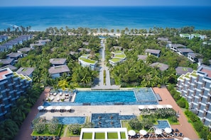 A resort with multiple buildings, a central swimming pool, and a view of the ocean. - Novotel Phu Quoc Resort (Phu Quoc)