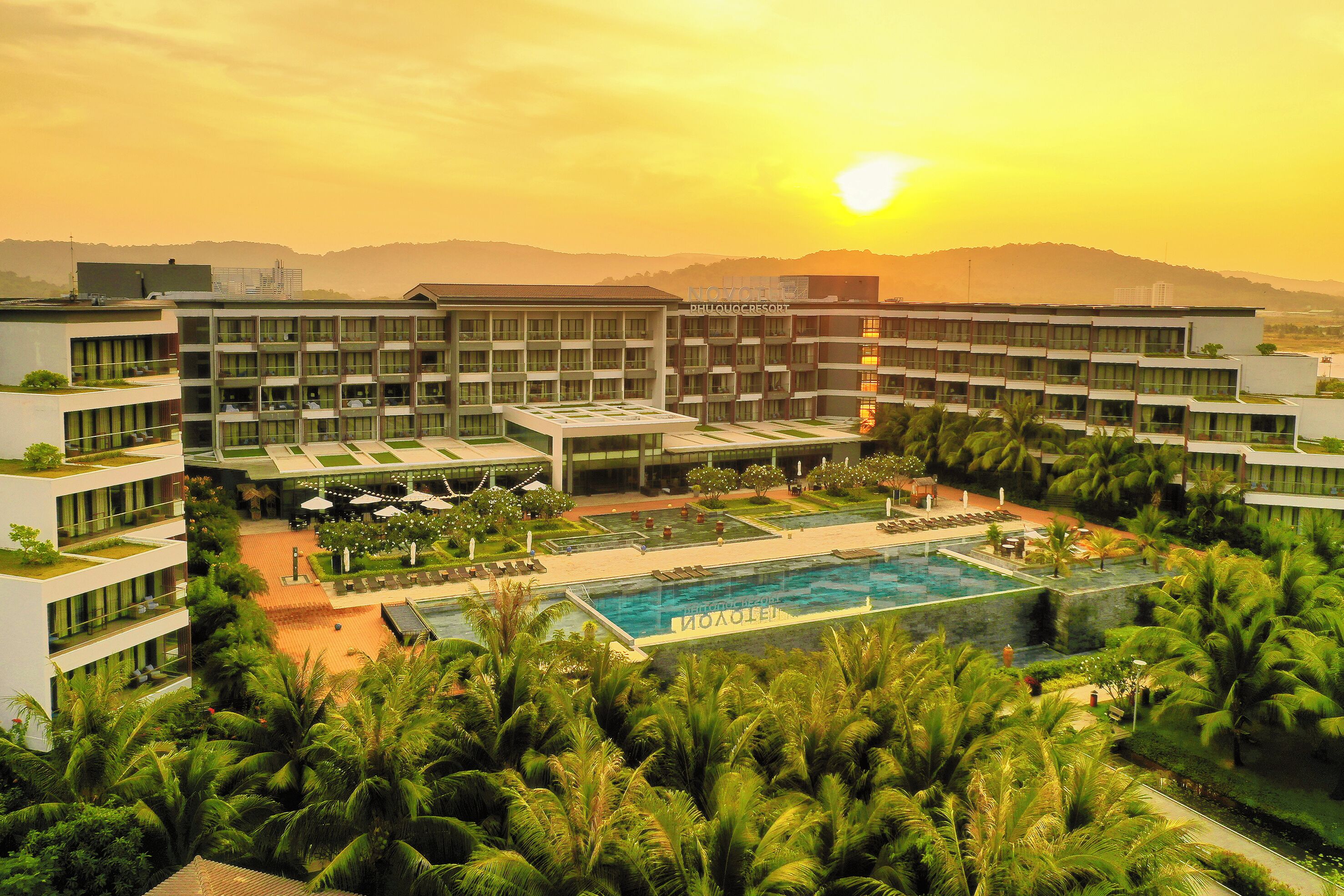 Un hôtel doté d’une piscine, d’une végétation luxuriante et offrant une vue imprenable sur le coucher de soleil.