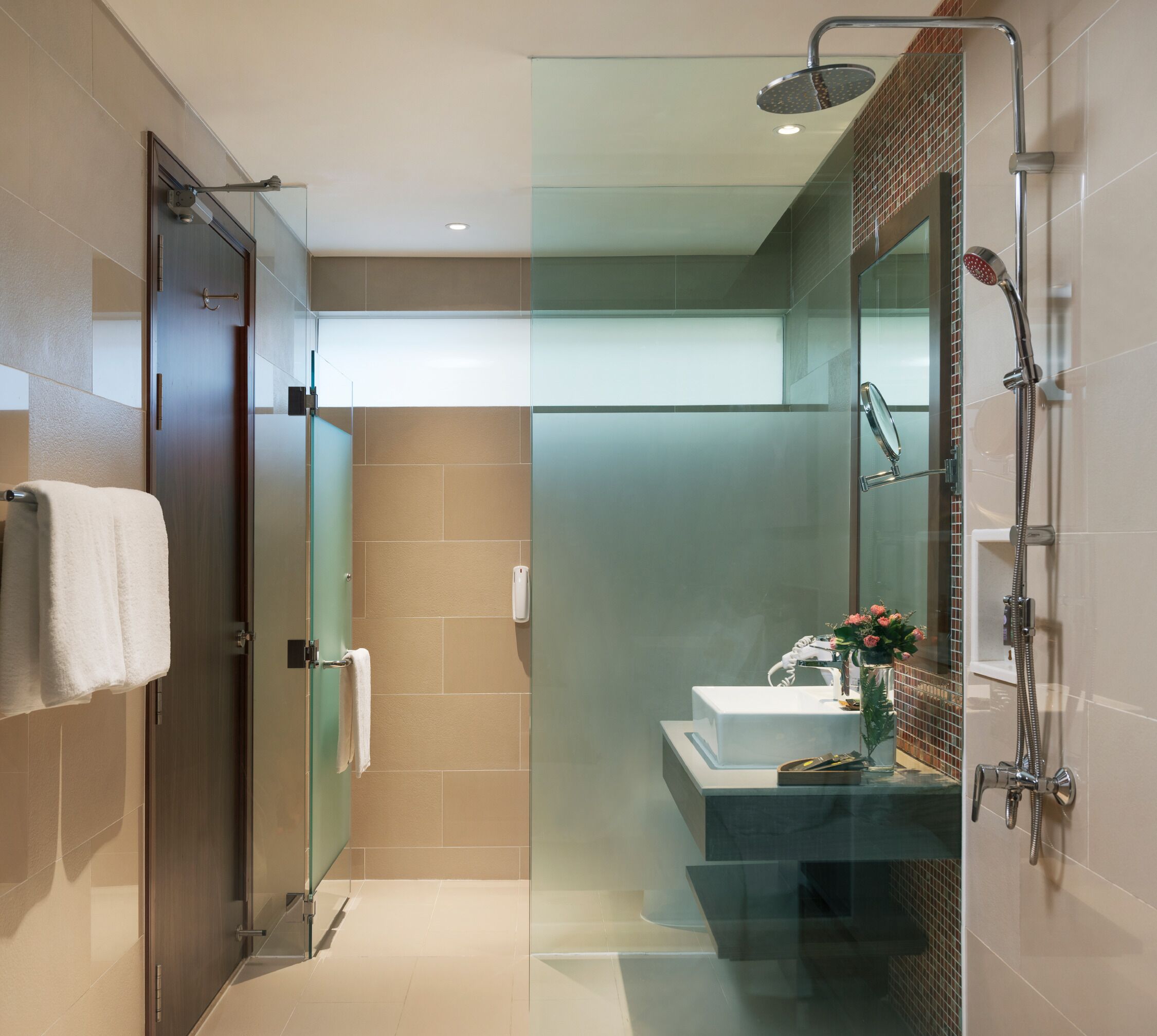 A modern bathroom with a glass-enclosed shower, a sink with a mirror, and a towel rack.
