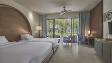 A hotel room with two beds, a desk, a chair, a TV, and a large window with curtains.