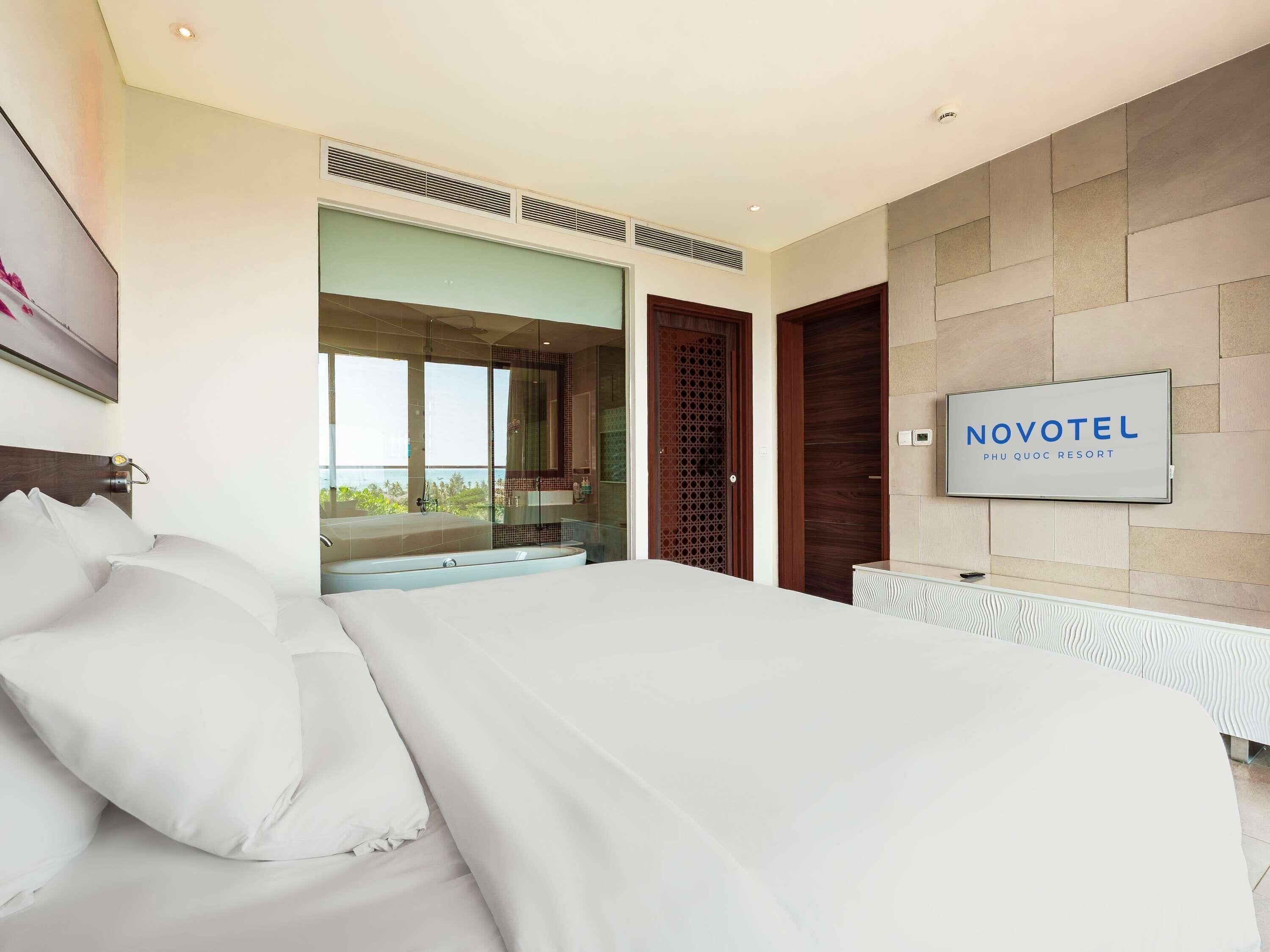 Une chambre d’hôtel moderne avec un grand lit, une télévision et une vue sur l’extérieur.