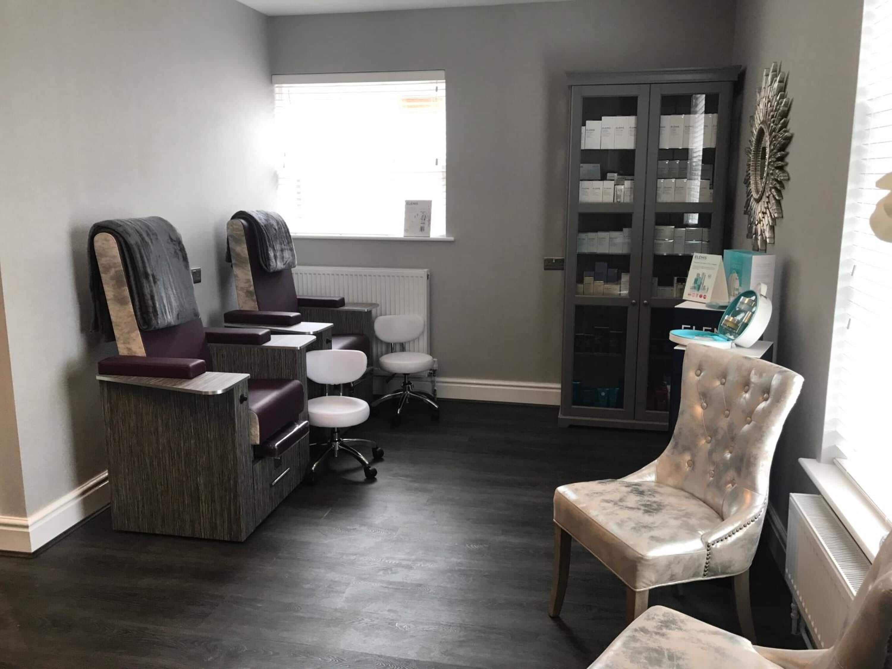 Un salón con piso de madera oscura, un espejo grande y una zona de estar con sillas y un tocador.