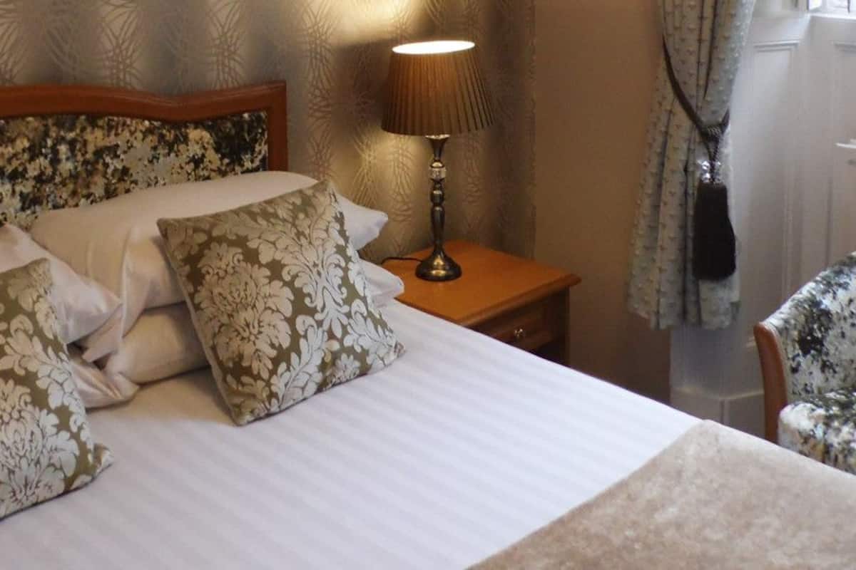 Una cama bien tendida con almohadas de estampado floral y un cabecero de madera.