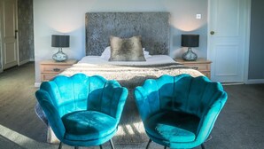 A bedroom with a large bed, two nightstands, two lamps, and two teal chairs. - Shaw Hill Golf Resort & Spa Hotel (Chorley)