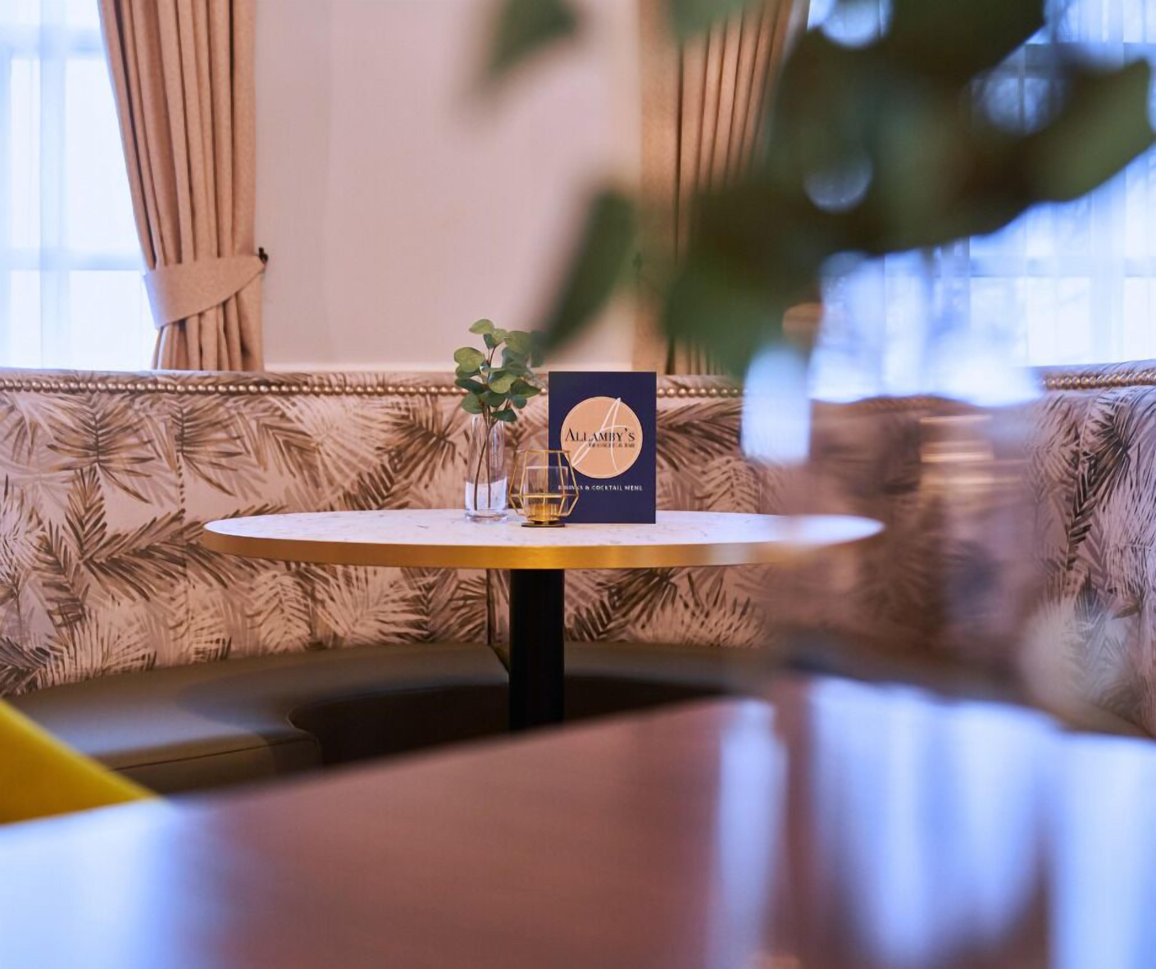 A round table with a menu and a glass of water on a patterned sofa.
