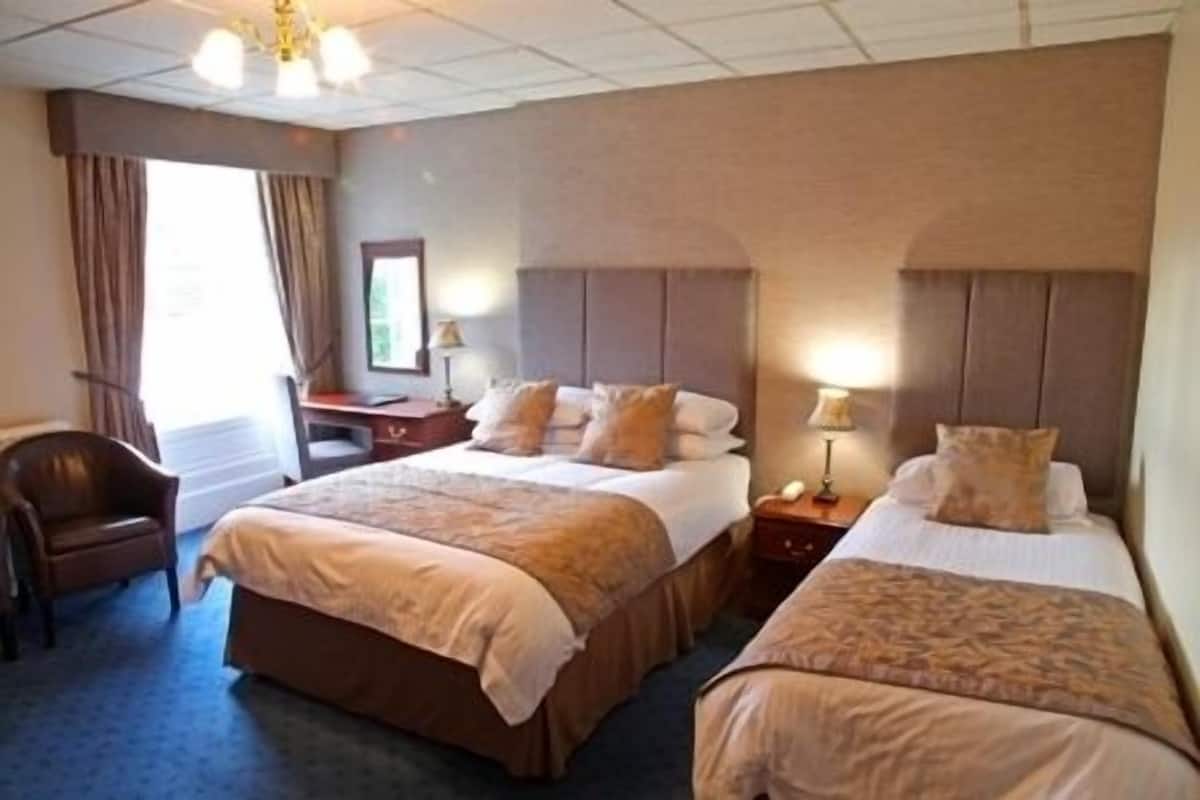 Habitación de hotel con dos camas, un escritorio y una silla.