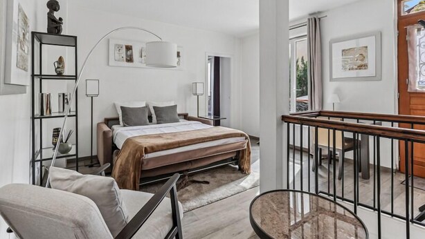 A modern bedroom with a bed, bedside tables, a chair, a desk, and a balcony. - Loft Fraternité (Bagnolet)