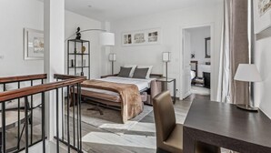 A modern hotel room with a bed, a desk, a chair, a lamp, and artwork on the walls. - Loft Fraternité (Bagnolet)