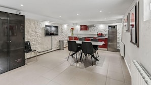 A modern kitchen with a dining area, equipped with a refrigerator, microwave, and a flat-screen TV. - Loft Fraternité (Bagnolet)