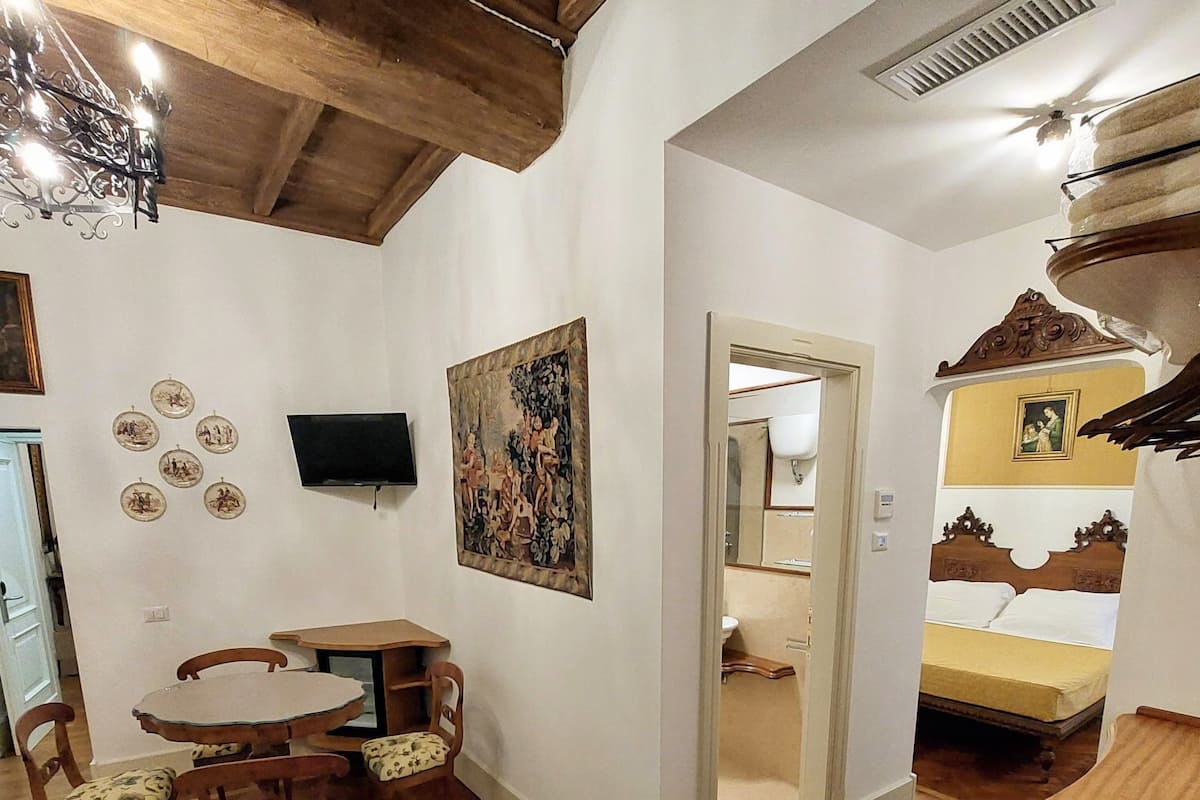 Una habitación con una mesa de comedor de madera, sillas, un televisor y un cuadro en la pared.