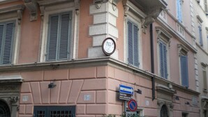 A pink building with a balcony, a door, and a sign indicating a place of worship. - Arpinelli Relais (Rome)