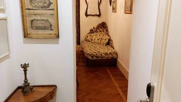 A hallway with a wooden floor, a vintage-style chair, and a small table with a candle holder.