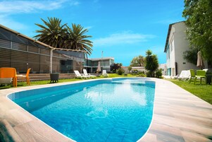 Una piscina al aire libre, sillones reclinables de piscina