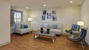 A living room with a sofa, armchair, coffee table, and a lamp.