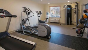 Et fitnessrum med løbebånd, crosstrainer og styrkemaskiner.