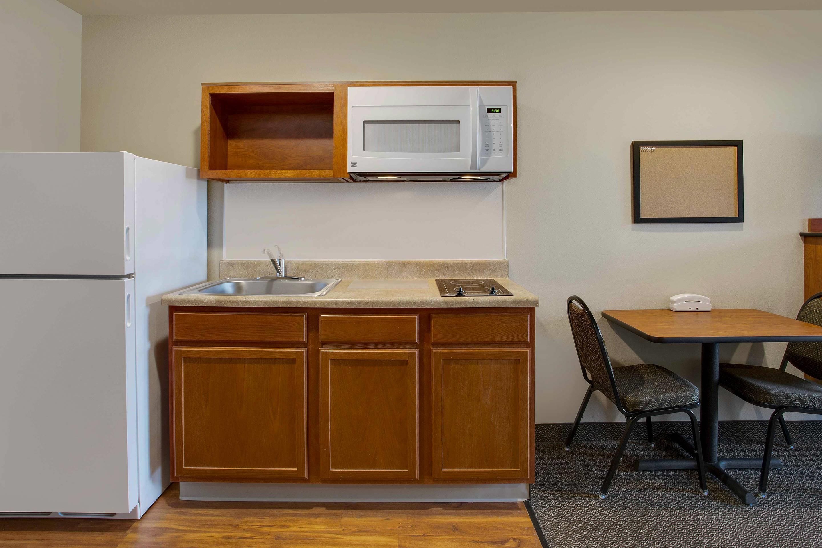 A compact kitchenette with a microwave, sink, and a small dining area with a table and chairs.