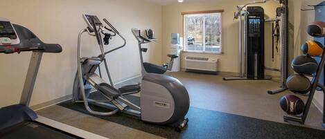 Une salle de sport équipée de machines de cardio, de matériel de musculation et d’un distributeur d’eau.