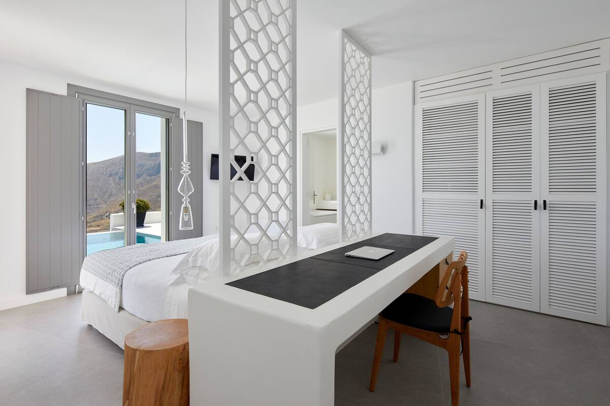 A modern bedroom with a bed, a desk, and a view of a mountain.