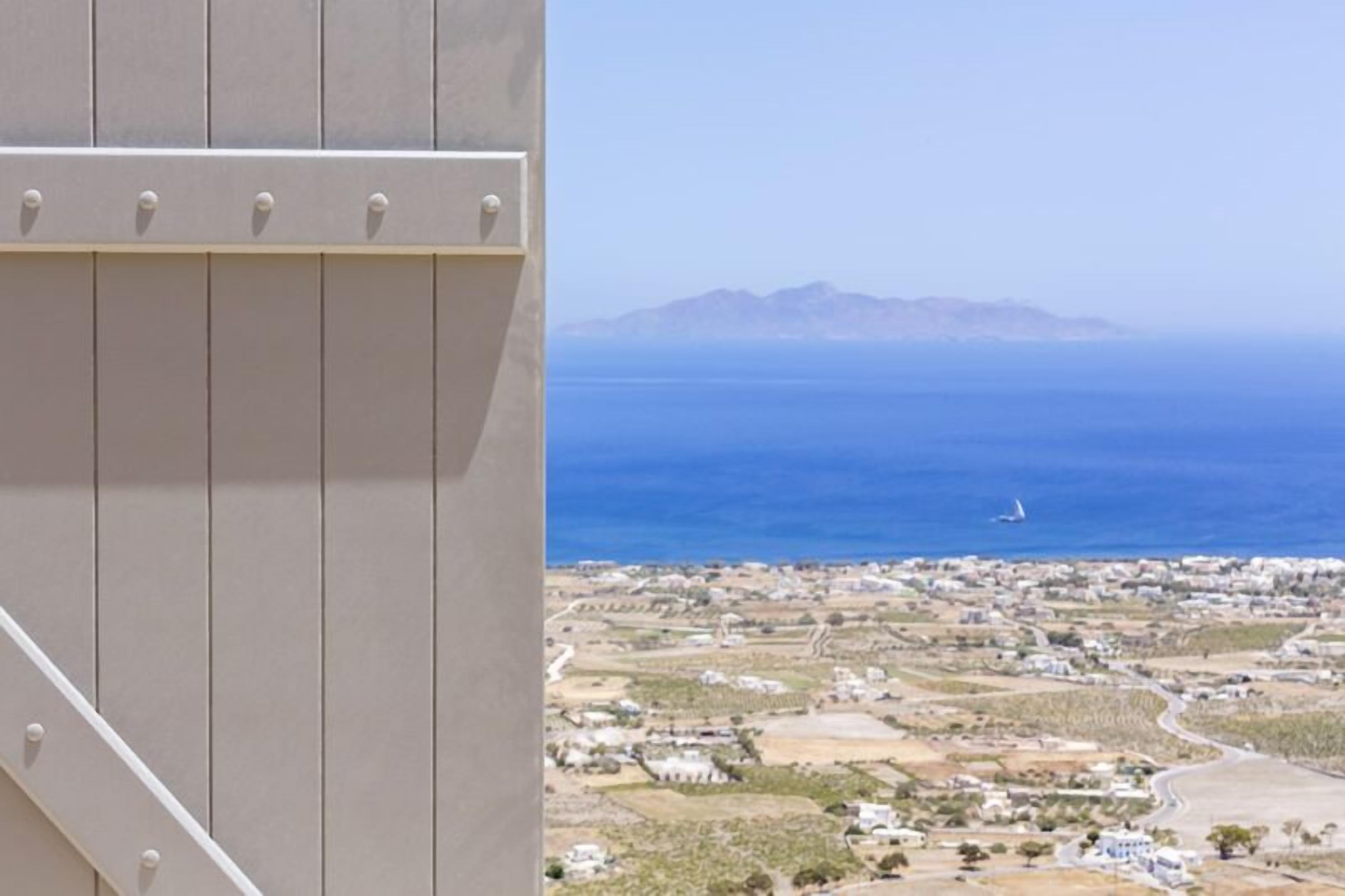 Un borgo costiero con vista sul mare e montagne in lontananza.