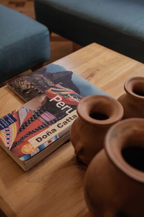Um livro intitulado 'Doña Catt' e três vasos de barro sobre uma mesa de madeira.