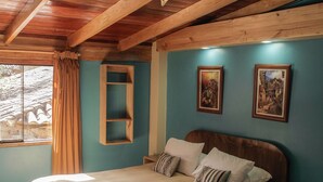 Une chambre avec un plafond en bois, un lit avec une literie blanche, une table de chevet et deux tableaux accrochés au mur.