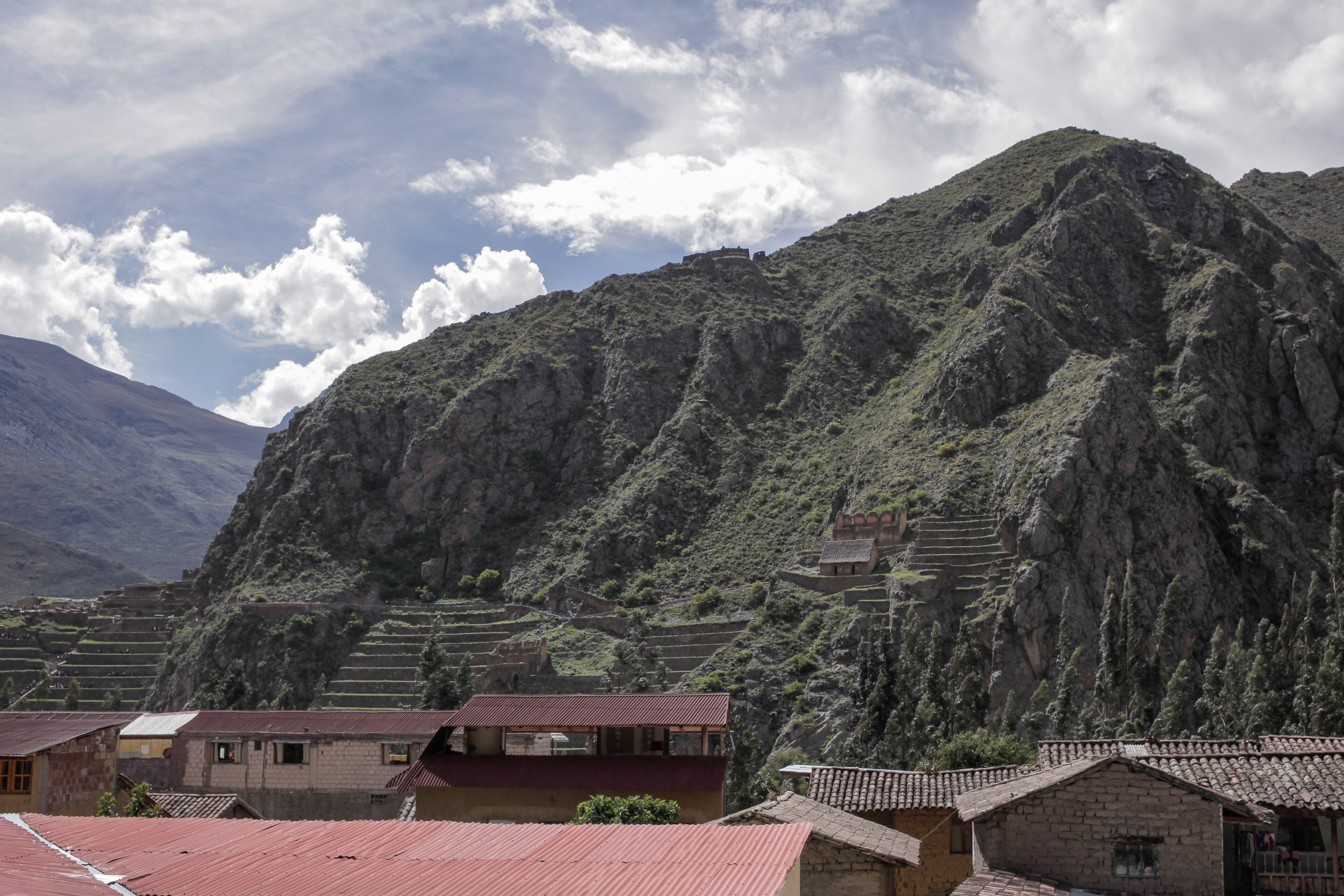 Un paisaje montañoso con campos en terrazas y edificios tradicionales con tejados rojos.