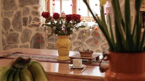 Une table à manger ornée d’un vase de fleurs, d’un saladier de fruits et d’une fenêtre agrémentée d’éléments décoratifs.