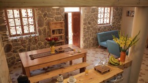 Une pièce chaleureuse avec une table en bois, des bancs, un canapé bleu et un mur en pierre.