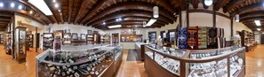A jewelry store with wooden beams on the ceiling, glass display cases, and various jewelry items. - Thunderbird Lodge (Chinle)
