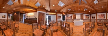 Un amplio comedor con mesas y sillas de madera, una zona de bar central y paredes decoradas con cuadros.