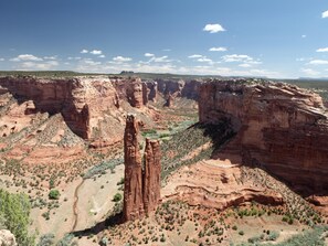 A canyon landscape with prominent red rock formations and sparse vegetation. - Thunderbird Lodge (Chinle)