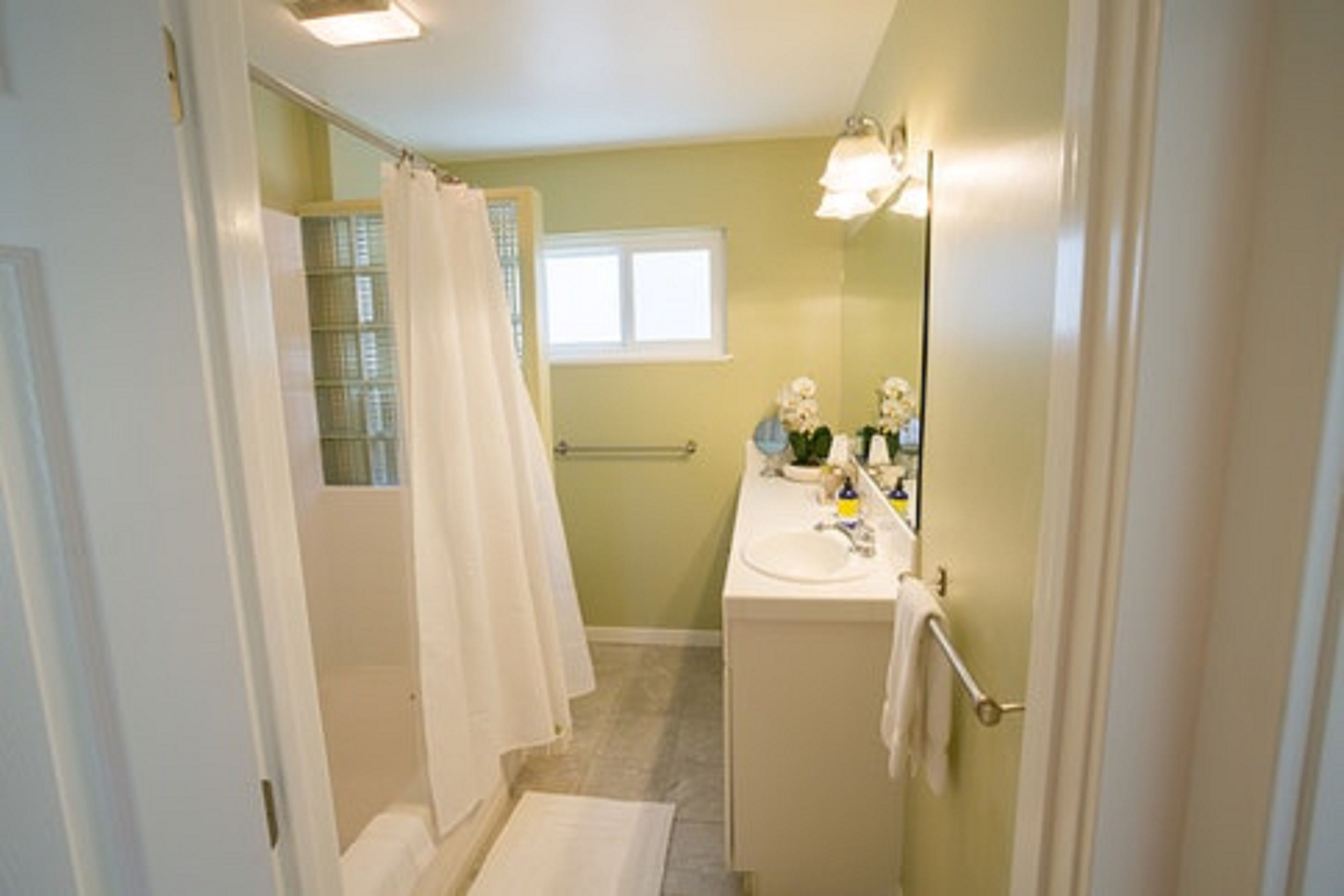 Un baño con ducha, lavamanos y ventana.