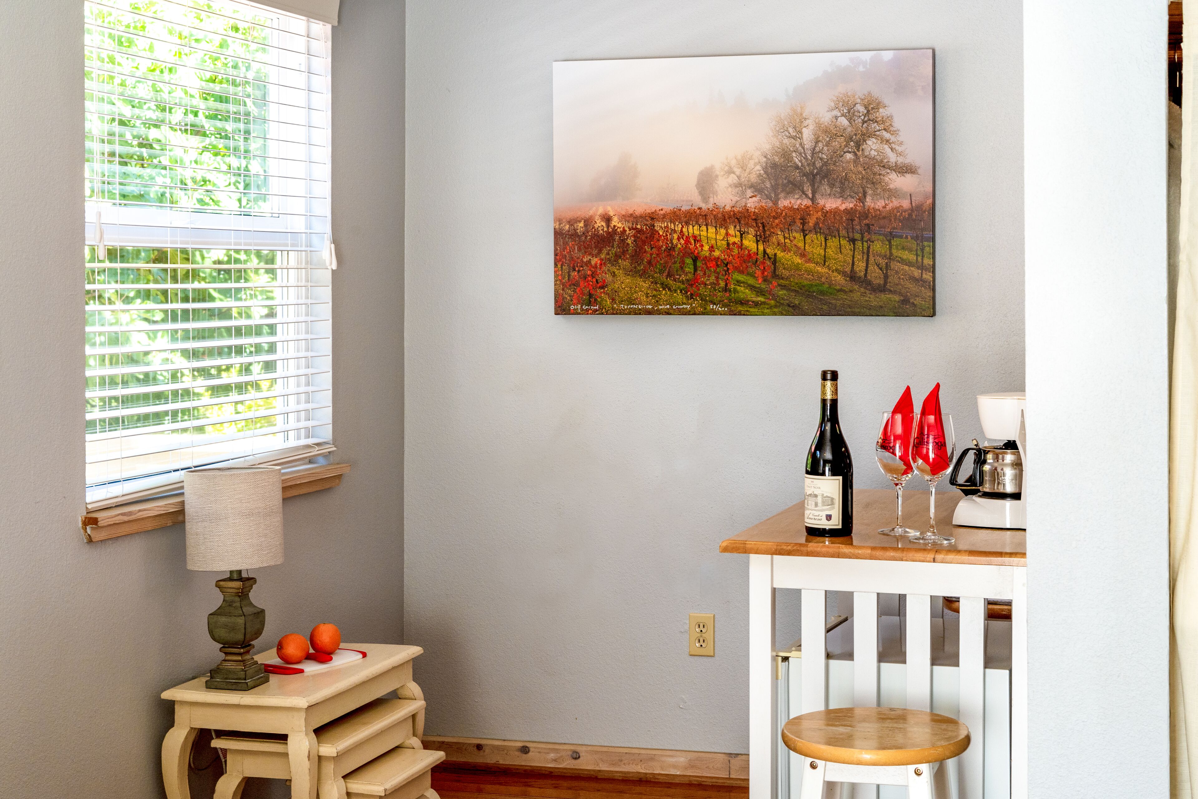 A room with a table, a lamp, a wine bottle, and glasses.
