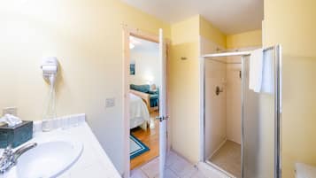Een badkamer met een wastafel, een haardroger en een douche.