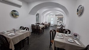 A restaurant with multiple tables, chairs, and a central archway. - Hotel São Miguel (Ponta Delgada)