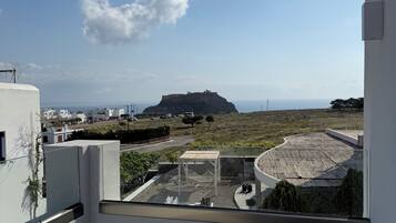 A balcony with a view of a hill and a building in the distance.
