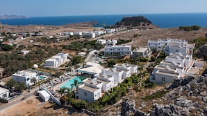 A coastal resort with modern white buildings, a swimming pool, and a view of the sea and rocky terrain. - Lambis Studios & Apartments (Rhodes)