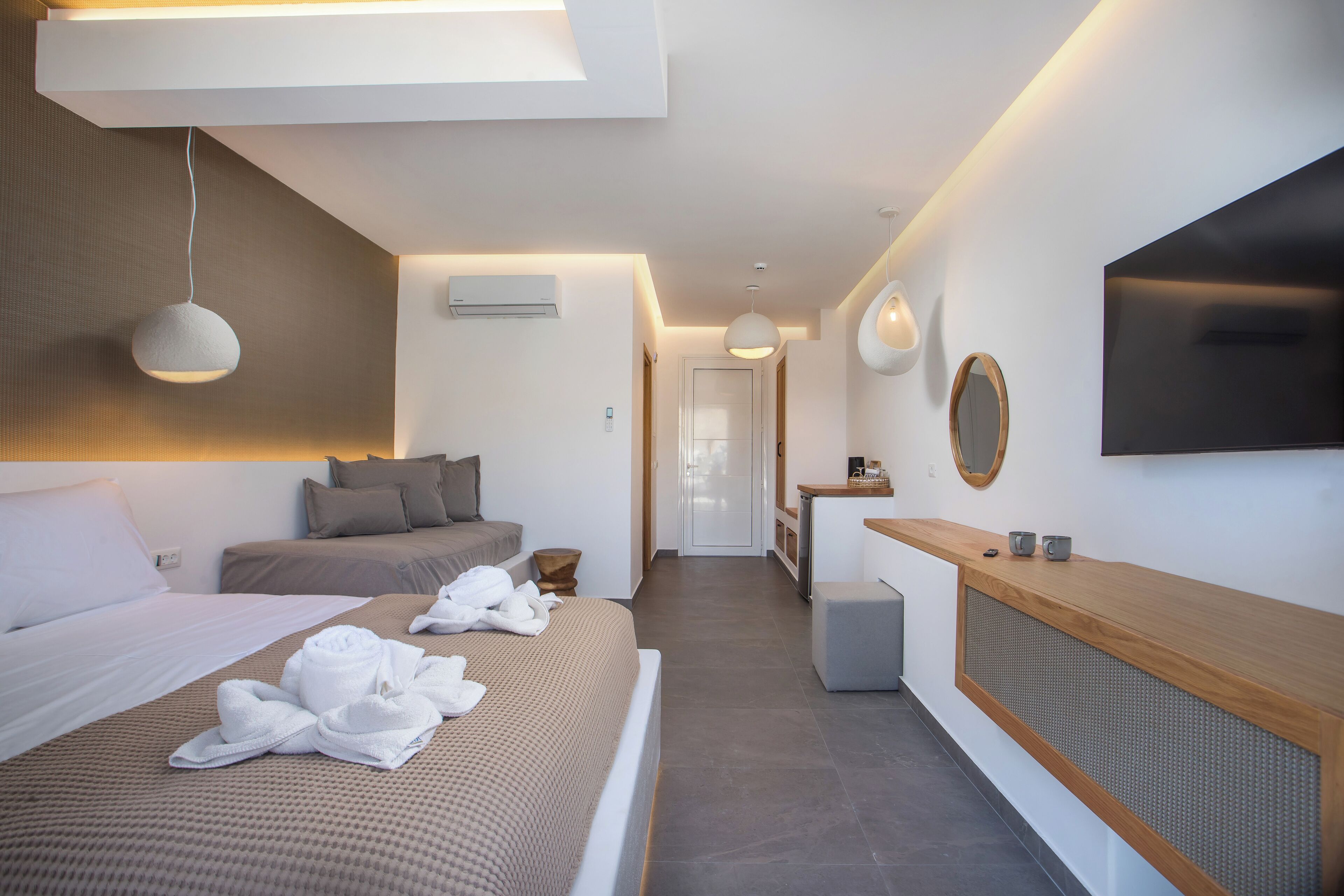 A modern hotel room with a large bed, a desk, a TV, and a bathroom.