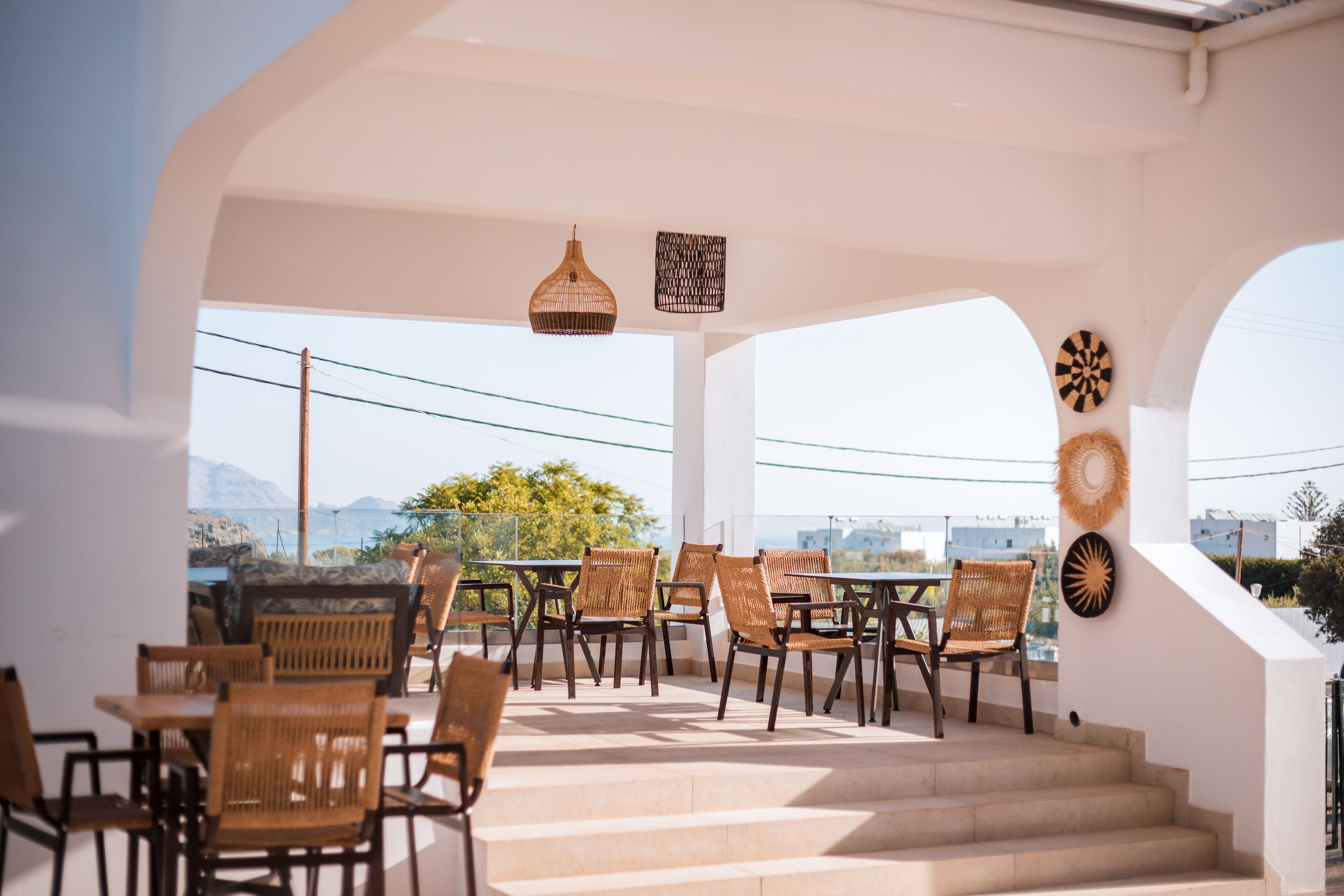 A terrace with wicker chairs and tables, a staircase, and decorative wall art.