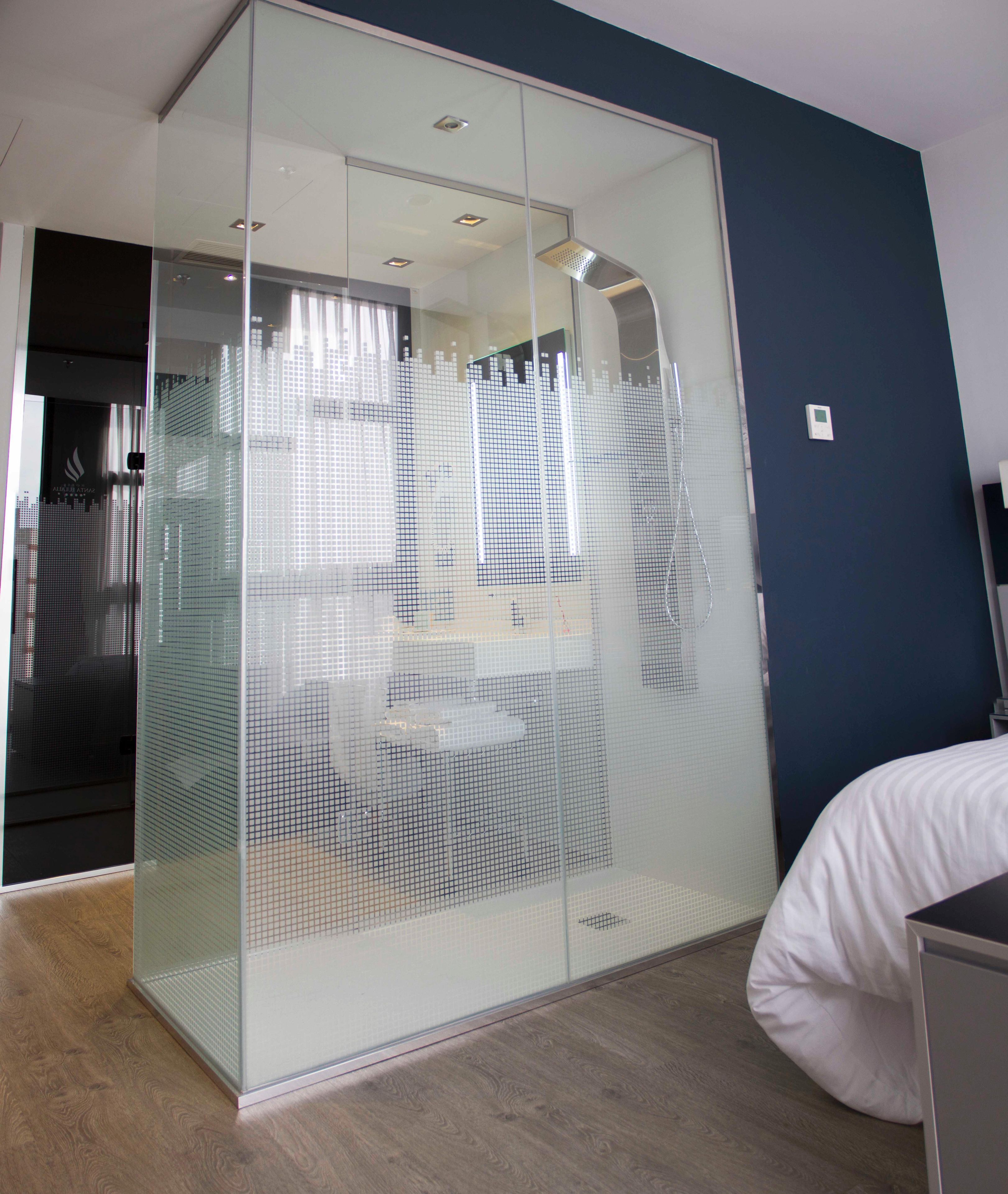 A room with a sliding glass partition, a bed, and a desk.