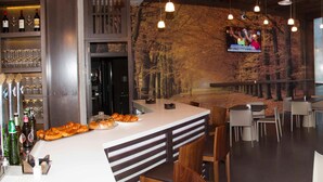 Un restaurant moderne avec un bar, des tables et un écran de télévision diffusant un programme d’information.