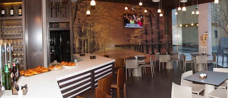 Un restaurante moderno con área de bar, asientos y una pantalla de televisión mostrando un noticiero.