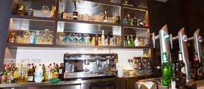 A bar area with shelves of liquor bottles and glasses, a coffee machine, and a tap. - Santa Eulalia Puertollano (Puertollano)