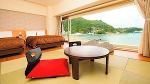A hotel room with a large window, a bed, a sofa, a table, and a red chair. - Ooedo Onsen Monogatari Toi Marine Hotel (Izu)